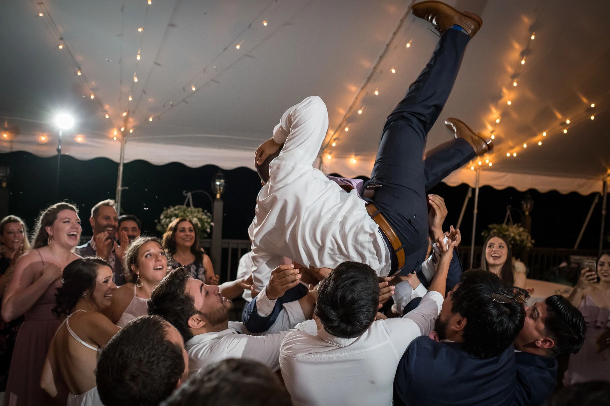 group of wedding guests dancing and throwing groom up in the air by wedding DJ by Champagne Toast at Zukas Hilltop Venue